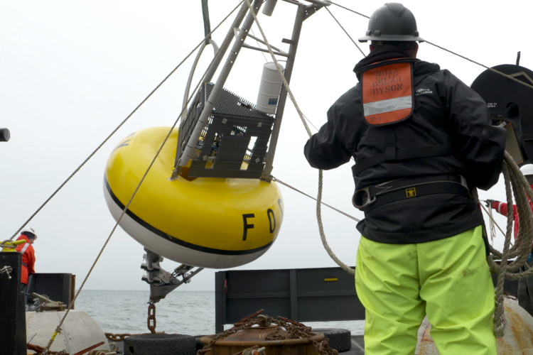 Large mooring named Peggy lifted by crane over port rail on the back deck of the NOAA Ship Oscar Dyson