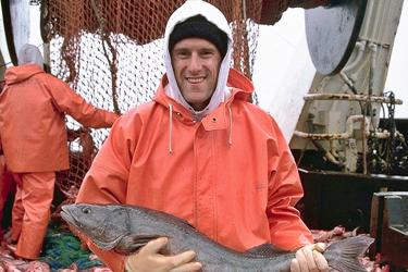 Scientist in orange suit holding a large fish